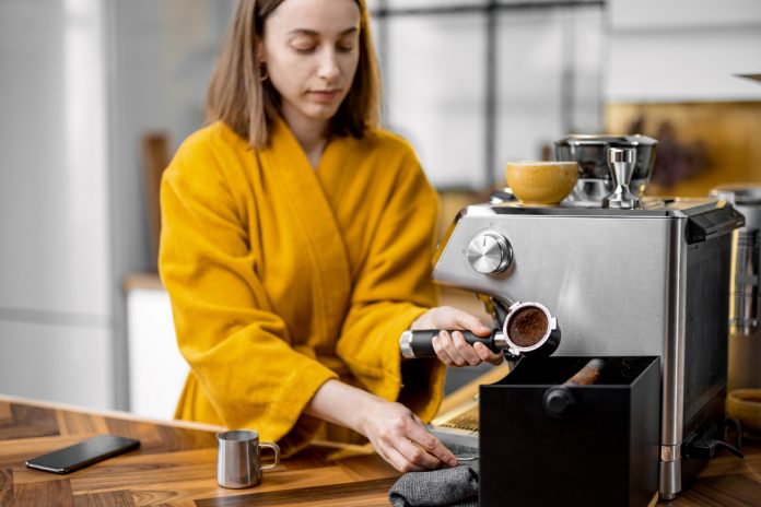 vrouw thuis koffie aan het maken met een koffiemachine